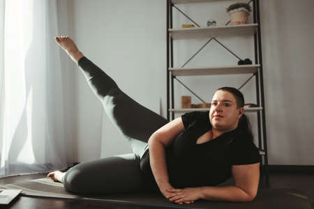 Overweight woman doing physical exercises at homeの写真素材