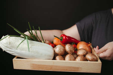 Woman holding box with vegetables and mushroomsの写真素材