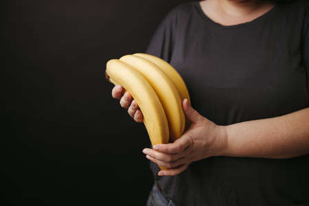Vegetarian lifestyle. Woman holding bananasの写真素材