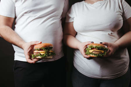 Overweight fat couple snack with tasty hamburgersの写真素材