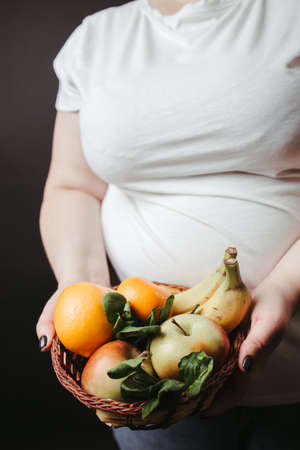 Healthy food. Fat woman with fresh fruitsの写真素材