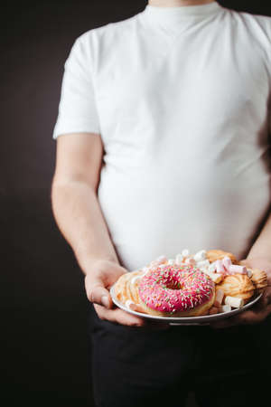 Overweight man with plate of sweets and cookiesの写真素材