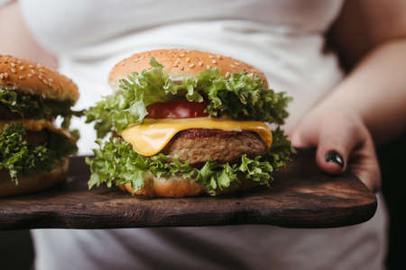 Obese woman with two tasty fattening hamburgersの写真素材