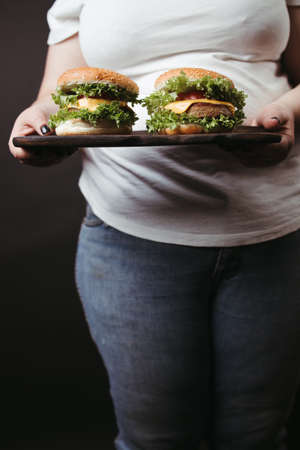 Obese woman with two tasty fattening hamburgersの写真素材
