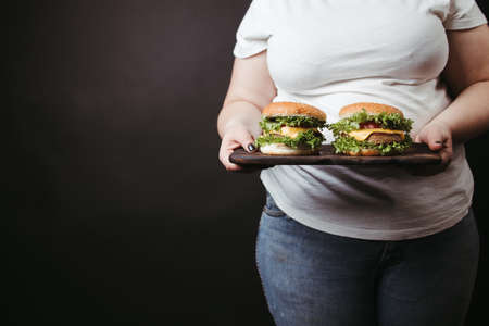 Obese woman with two tasty fattening hamburgersの写真素材