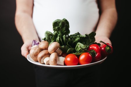Overweight man holding plate with fresh vegetablesの写真素材