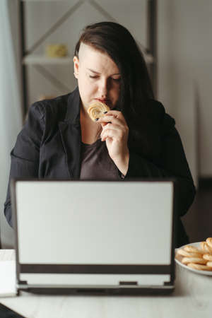 Unhealthy snack at work time, woman overeatingの写真素材