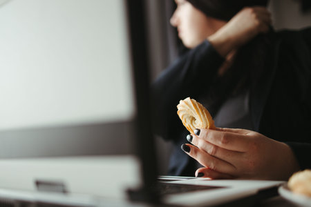 Woman multitasking eating sweets at her workplace