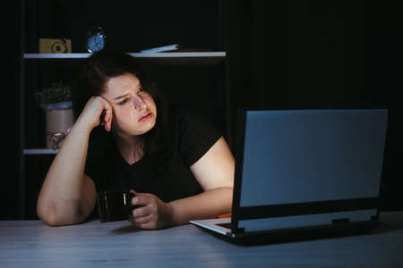 Tired bored lazy woman freelancer working at nightの写真素材