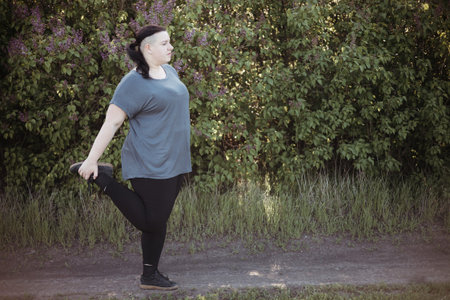Overweight woman warming up legs before jogging