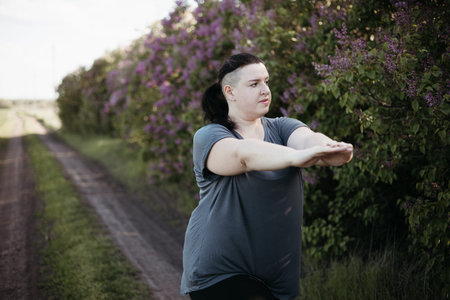 Overweight woman in sportswear training in nature