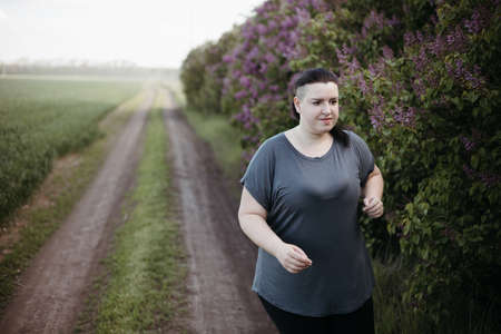 Overweight woman jogging outdoors at the open airの写真素材