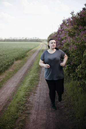 Overweight woman jogging outdoors at the open airの写真素材