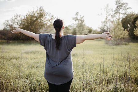 Overweight woman rising hands, view from the backの写真素材