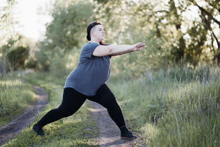Overweight woman in sportswear training in natureの写真素材