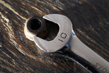 old nut and chrome wrench on wood plate, warm tone