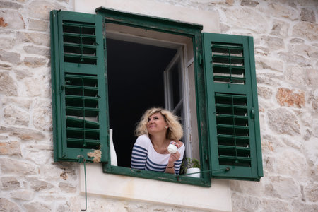 Beautiful blonde woman is looking into the distance with cup of coffee in her hands