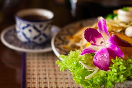 Beautifully served thai noodles with orchid and a cup of tea, shallow DOF, focus on the flowerの写真素材