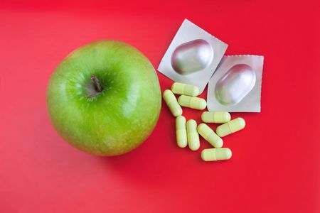 Green apple and various tablets over bright red backgroundの写真素材