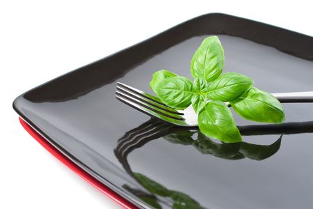 Basil leaves set with fork on plate, isolated on whiteの写真素材