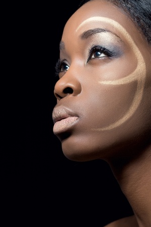 Beauty shot of a black fashion model with golden makeup, closeup, isolated on blackの写真素材