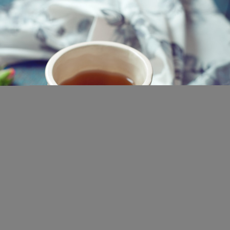 Cup of tea set with a beautiful tea towel and roses on a wooden table, toned photoの写真素材