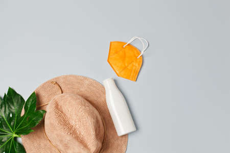 Beach accessories: straw hat, sunscreen lotion and FFP2 face mask, isolated on grey, flatlayの写真素材