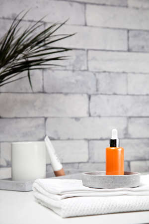 Face serum bottle on table at home bathroom. Minimal styling. Beauty blogging, skin care ad mock up with copy spaceの写真素材