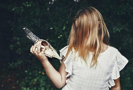 Gothic teenager girl with goat skull, her face is not visible under long hair. Youth subculture, Day of the Dead, Halloweenの写真素材