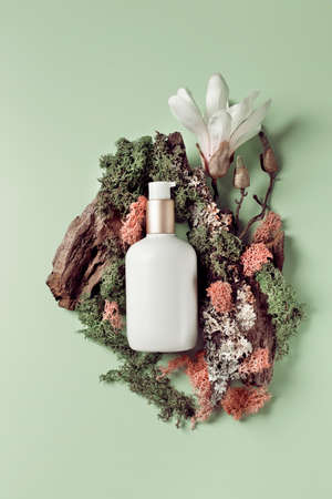 Beauty serum on pale green background with exotic flowers, top view flat lay. Minimalistic jacandi style, copy spaceの写真素材