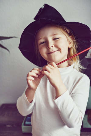 Little girl playing imaginative wizard game at home and wearing a magic hat. Casting a spellの写真素材