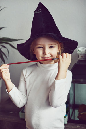 Little girl playing imaginative wizard game at home and wearing a magic hat. Play pretendの写真素材