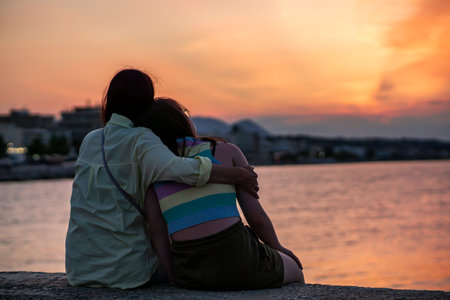 Mother and daughter watching a sunset in Greeceの写真素材