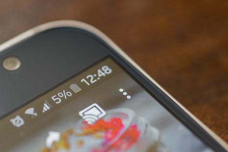 Smartphone with five percent battery charge on the screen.