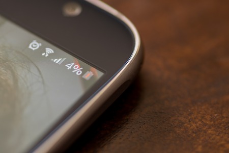 Smartphone with four percent battery charge on the screen.の写真素材