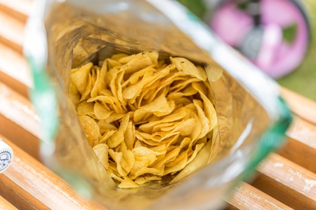 potato crisps in bag on wooden bench outdoorの写真素材
