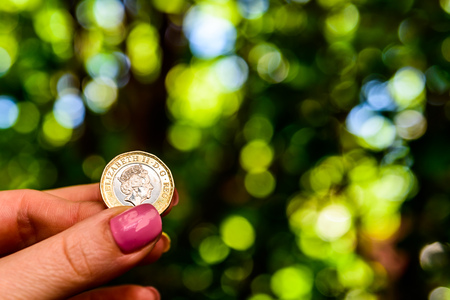 Female hand holding new british one sterling pound coinの写真素材