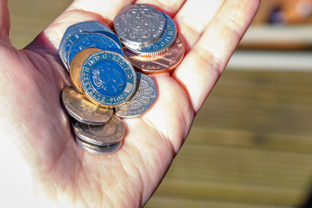 Female hand holding new british one sterling pound coinsの写真素材