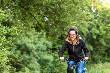 Mother with son riding bike in summer parkの写真素材