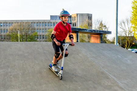Day view teen boy riding scooter on skating playgroundの写真素材