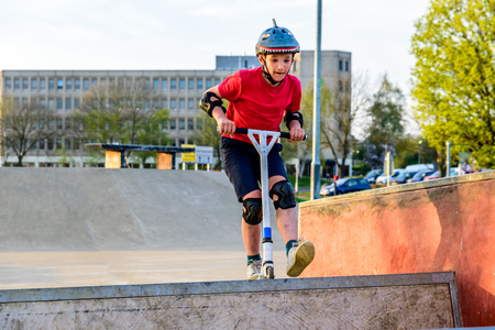 Day view teen boy riding scooter on skating playgroundの写真素材