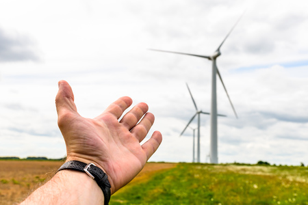 Human hand aiming to wind power turbines generate electricityの写真素材