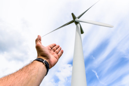Human hand aiming to wind power turbines generate electricityの写真素材