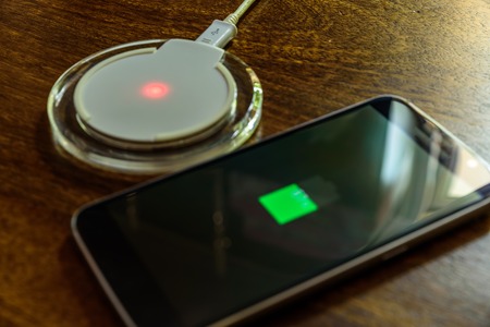 Smartphone charging on a charging pad. Wireless chargingの写真素材