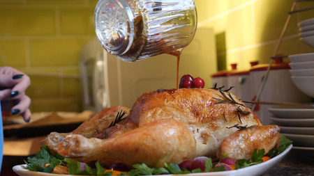 Female Hands Decorate Roasted Whole Chicken on Plate For Family Dinner.の写真素材