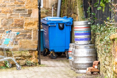 Day view of stacked beer casks of kegs at the back of the pub with recycly bin and shopping trolley next to itの写真素材