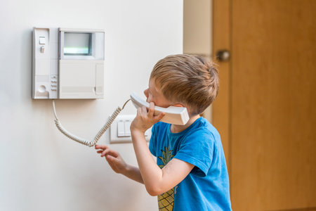 Day view blond boy talking via intercom in UK