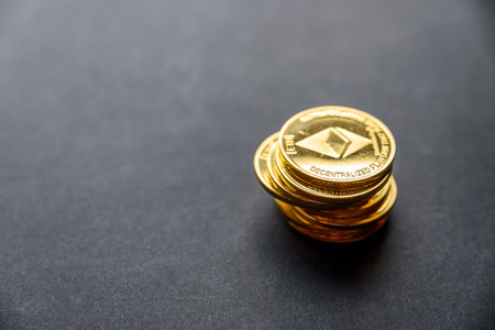 Golden virtual money Ethereum crypto currency coins stacked on a dark backgroundの写真素材