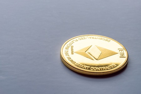 Golden virtual money Ethereum crypto currency coin on a dark backgroundの写真素材