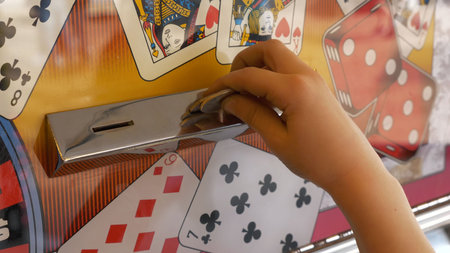 Close-up Of Childs Hands Inserting Coin Into Slots Machineの写真素材